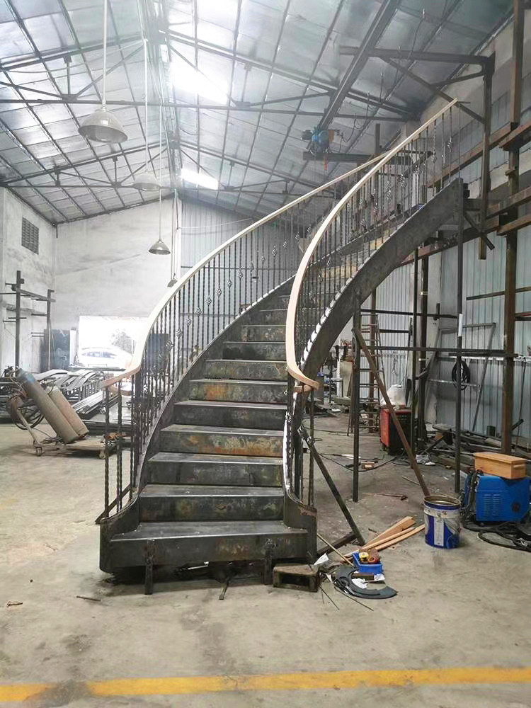 classic curved staircase with iron railing under production